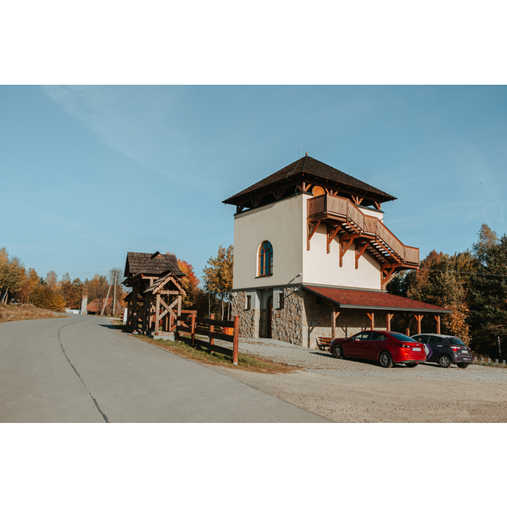 A red and black car by a bright building with wooden stairs next to an asphalt road