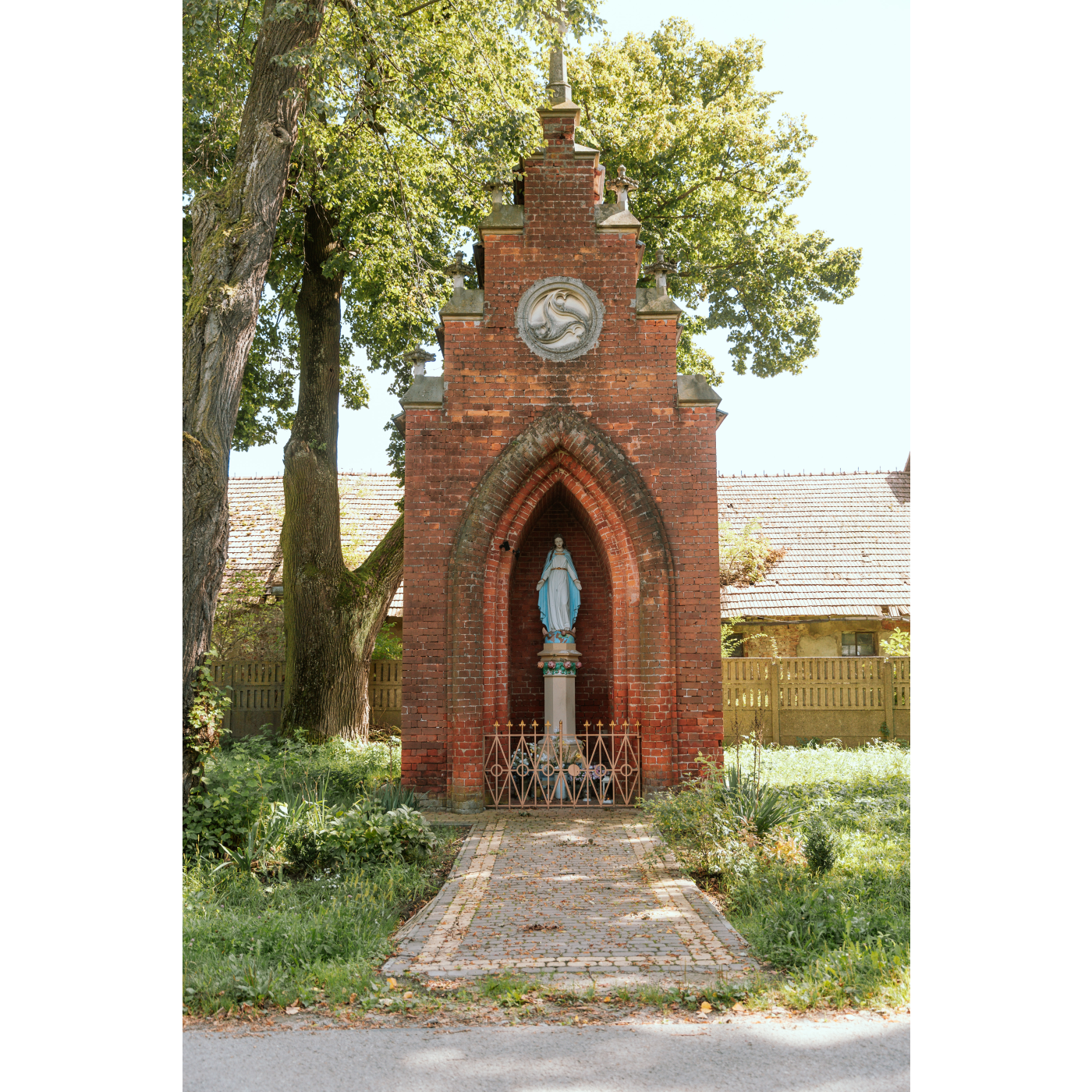 Kapliczka zbudowana z czerwonej cegły z figurką Matki Boskiej