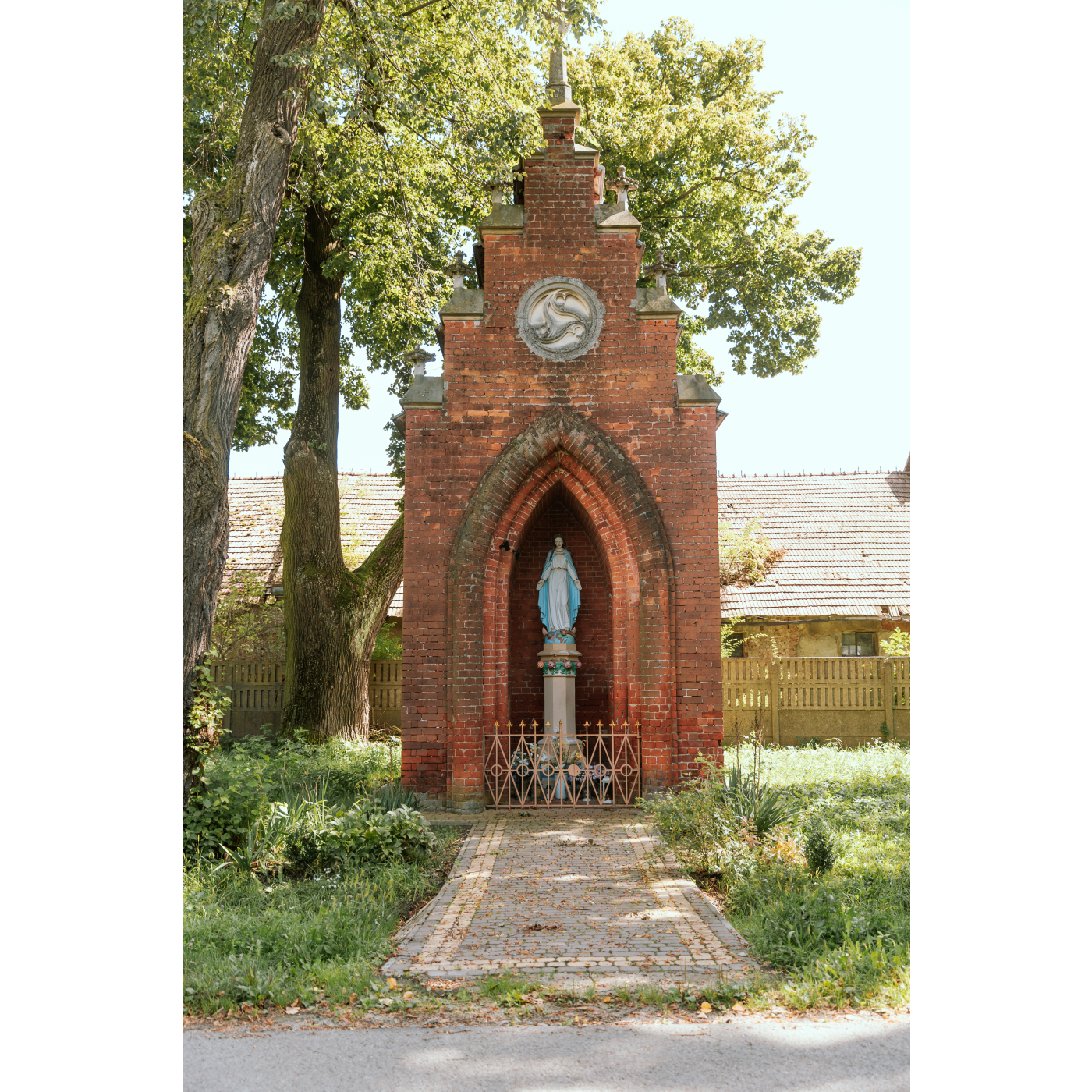 A chapel built of red brick with a statue of the Virgin Mary